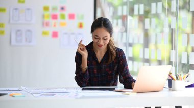 Yaratıcı ofiste mobil uygulama yazılım tasarımı için çalışan genç bayan UX tasarımcısı.