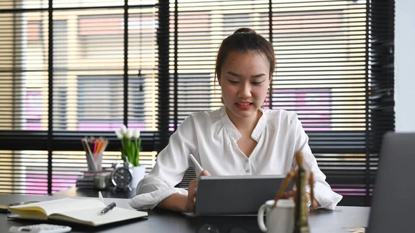 Asian businesswoman sitting at modern workplace and using digital tablet — Stock Photo, Image