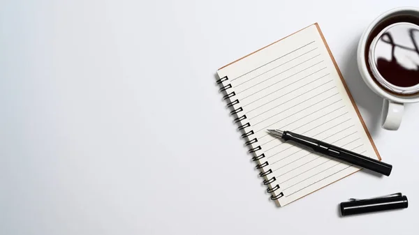 Cuaderno, taza de café y bolígrafo sobre fondo blanco. Vista superior con espacio de copia —  Fotos de Stock