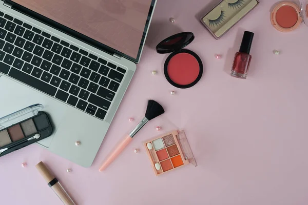 Espace de travail féminin avec ordinateur portable et cosmétiques sur fond rose — Photo