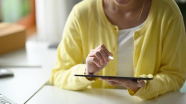 Evde çalışan ve dijital tablet kullanan, günlük giysiler içinde vurulan yaratıcı kadın.