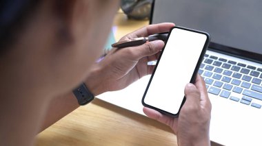 Yakın çekim adamı rahat bir iş yerinde çalışıyor ve cep telefonu kullanıyor.