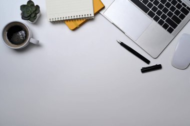 Dizüstü bilgisayar, gözlük, kahve fincanı, defter ve beyaz masanın üzerindeki sulu bitki. Düz yatış, Üst Görünüm