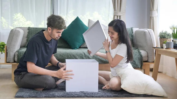 Genç çift oturma odasında karton kutuları açıyor. Yerleştirme evi yenileme, kaldırma konsepti