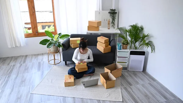 Desde arriba ver a las mujeres jóvenes vendedor en línea preparando cajas de paquetes de producto para la entrega a los clientes. Comercio electrónico, concepto de venta en línea — Foto de Stock