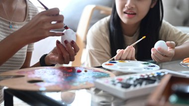 Kırpılmış fotoğraf, Paskalya için hazırlanan beyaz yumurtalarla resim yapan anne ve kız çocuğu..