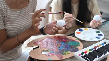 Kırpılmış anne ve kızı Paskalya 'ya hazırlanırken beyaz yumurtalar çiziyor..