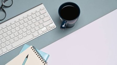 Kablosuz klavye, kahve fincanı ve not defteri ofis masasının üzerinde duruyordu..