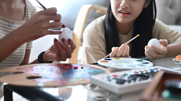 Kırpılmış fotoğraf, Paskalya için hazırlanan beyaz yumurtalarla resim yapan anne ve kız çocuğu..