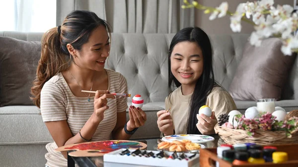 아시아의 젊은 어머니와 딸 이 부활절 기념행사를 준비하는 달걀을 그리고 있다. 부활절, 휴일, 사람들의 개념. — 스톡 사진
