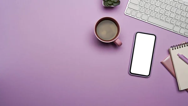 Telefone celular com tela em branco, xícara de café e suprimentos em fundo roxo. — Fotografia de Stock