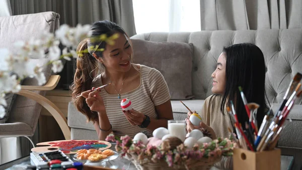 아름다운 아시아인 어머니와 그녀의 딸은 부활절 축제를 축하하며 달걀을 함께 그리고 있습니다. 부활절 휴일 개념. — 스톡 사진
