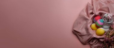 Renkli Paskalya yumurtaları ve pembe arka planda bahar çiçekleri fotokopi alanı ile. Paskalya Günü için selamlar ve hediyeler.