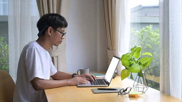 Vista lateral enfocado asiático hombre freelancer trabajando en línea, la lectura de correo electrónico en el ordenador portátil en casa — Foto de Stock