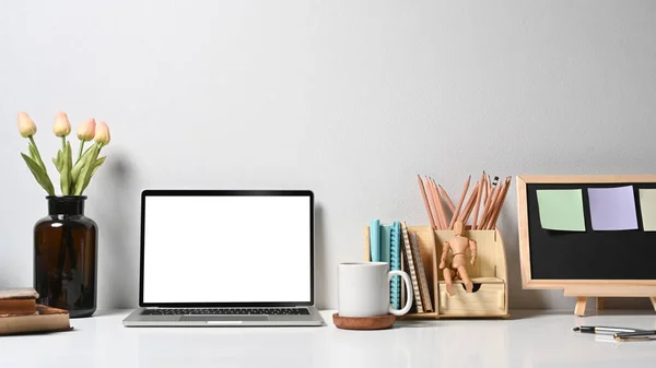 Local de trabalho criativo designer com computador portátil, vaso de flores, xícara de café e artigos de papelaria na mesa branca — Fotografia de Stock