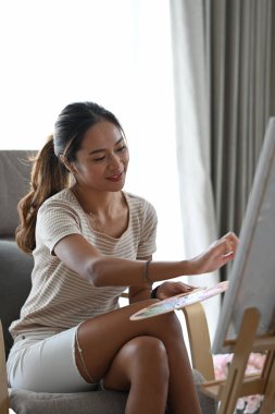 Çekici genç bir kadın boş zamanlarını evde geçiriyor ve suluboya resimler yapıyor..