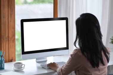 Parlak modern işyerinde bilgisayar kullanan iş kadınının arka görünümü.