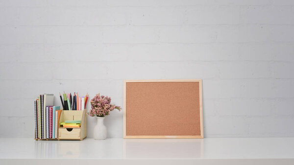Empty wooden board, stationery and dry flowers on white table.