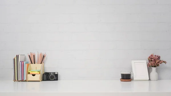 Lieu de travail élégant avec appareil photo, tasse à café, cadre photo et papeterie sur table blanche. — Photo