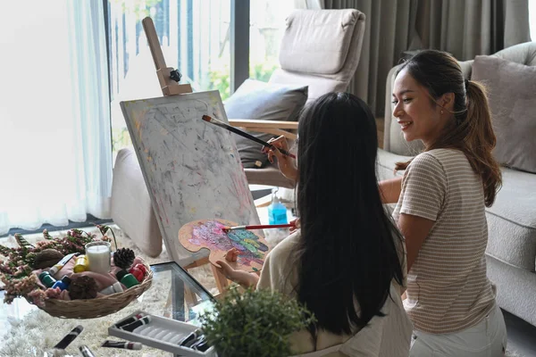 Back view of asian girl enjoy painting picture with her mother at home. — Stock Photo, Image