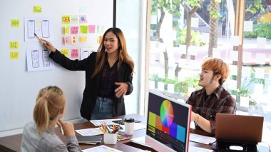 Web geliştirici ekibi ofiste mobil uygulama yazılım tasarımı projesi üzerinde çalışıyor ve beyin fırtınası yapıyor..