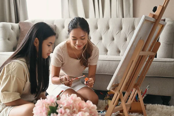 Happy young woman enjoy painting picture with her young sister at home. — Stock Photo, Image