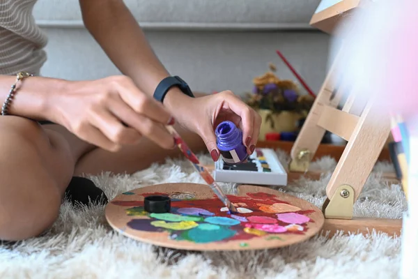 Zugeschnittene junge Frau hält Pinsel und mischt Ölgemälde auf Palette. — Stockfoto