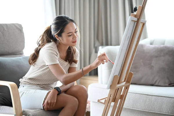 Jeune femme détendue assise devant le chevalet et peinture tableau sur toile. — Photo