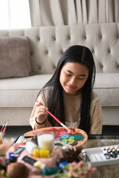 Souriant asiatique fille tenant pinceau peinture et mélange peinture à l'huile de couleur sur la palette. — Photo