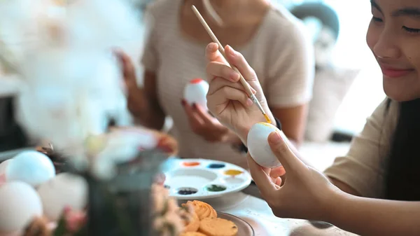 Joyeux asiatique fille peinture oeufs de Pâques à la maison. Pâques, vacances et concept de personnes. — Photo