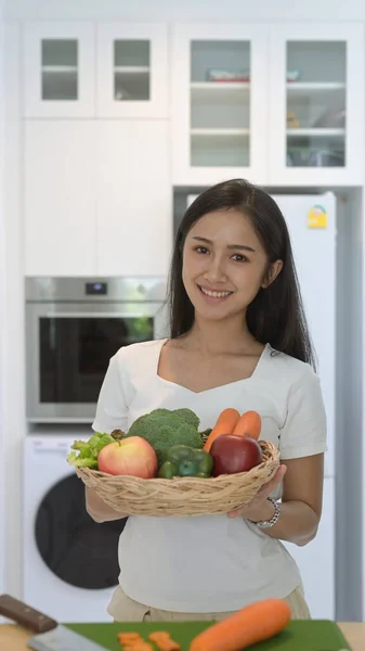 Portret aziatische vrouw met rieten mand met verse biologische groenten en fruit staan in huis kantoor — Stockfoto