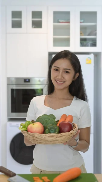 Retrato mulher asiática segurando cesta de vime com legumes orgânicos frescos e frutas de pé em casa escritório — Fotografia de Stock