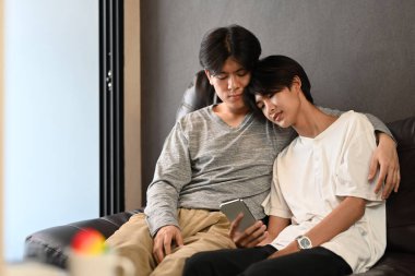 Sevgili erkek çift birbirlerine sarılıyor ve evde birlikte vakit geçiriyorlar. LGBT, gurur, ilişkiler ve eşitlik kavramı