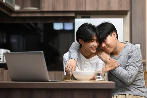 Солодка гомосексуальна пара з щасливою ранковою розмовою і обійнята сидячи на кухні — стокове фото