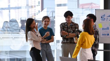 Genç iş adamları beyin fırtınası yapıyor ve yaratıcı ofiste önemli bir proje üzerinde çalışıyorlar..