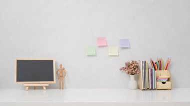 Ön manzara tahtası, saksı bitkisi ve kırtasiye malzemesi beyaz masada. Bilgi içeriğiniz için alanı kopyalayın.