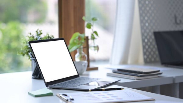 Стол для домашнего офиса с ноутбуком, кофейной чашкой, принадлежностями и комнатным стеклом.