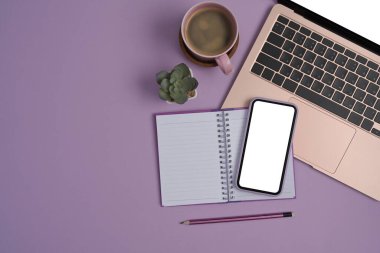 Mor arka planda cep telefonu, dizüstü bilgisayar, defter ve kahve fincanı..