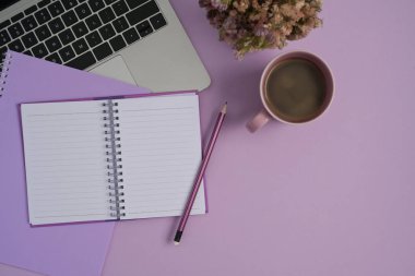 Mor arka planda dizüstü bilgisayar, defter ve kahve fincanı vardı..