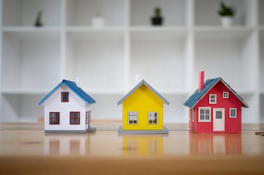 Mimarlar masasında üç küçük ev modeli. Yeni ev, sigorta ve emlak konsepti