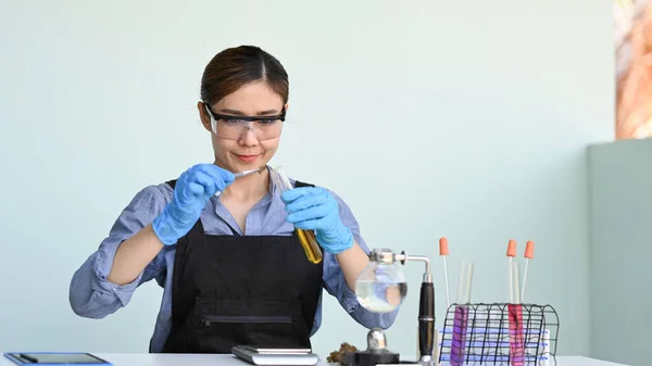 Inyección de investigador poniendo muestra seca de cannabis en frasco y tubos con sustancias coloridas en la mesa. Medicina alternativa herbal, concepto de aceite de cbd —  Fotos de Stock