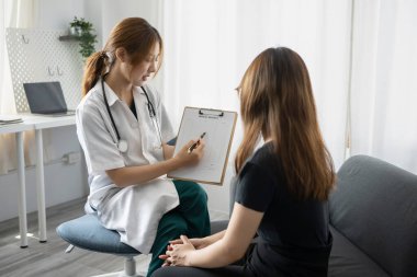 Beyaz üniformalı kadın doktor hastaya profesyonel danışmanlık yapıyor. Sağlık ve Tıp Konsepti.