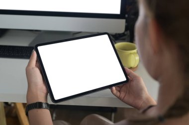 Omuz üstü yakın çekim görüntüsü. Elinde boş ekranlı dijital tablet tutan genç kadın..