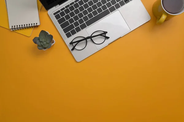 Snygg arbetsplats med dator bärbar dator, anteckningsblock, glasögon och kaffekopp på gul bakgrund. Ovanifrån, Flay låg, Kopiera utrymme. — Stockfoto