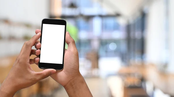 Uomo mani in possesso di smart phone con sfondo caffè offuscata. Schermo vuoto per montaggio display grafico. — Foto Stock