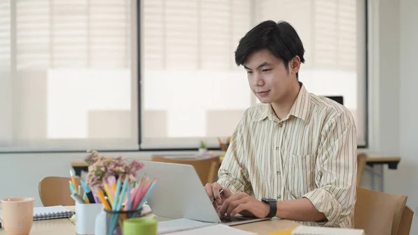 Asiatico maschio dipendente lavoro con computer portatile a moderno co lavoro ufficio spazio. — Foto Stock