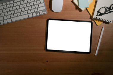 Boş ekranlı dijital tablet ve ahşap arka planda ofis malzemeleri. Düz yatıyordu.