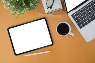 Dijital tablet, dizüstü bilgisayar ve sarı arkaplan üzerine not defterleri. Grafik görüntüleme kurgusu için boş ekran.