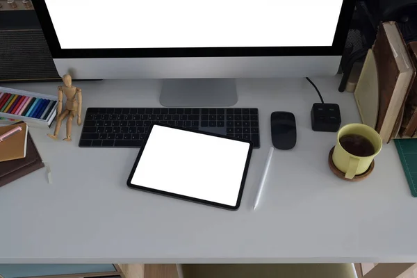 Creative designer workplace with digital tablet, computer, coffee cup and stationery on white table.