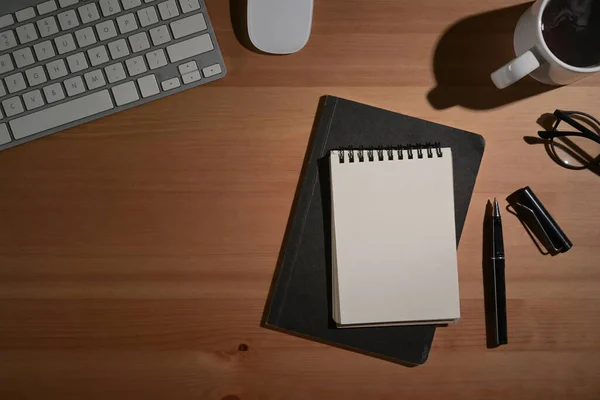 Vista dall'alto notebook vuoto, tastiera wireless, occhiali da vista e tazza di caffè su sfondo di legno. — Foto Stock